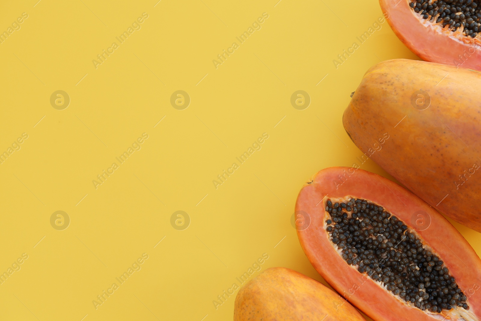 Photo of Fresh ripe cut and whole papaya fruits on light green background, flat lay. Space for text