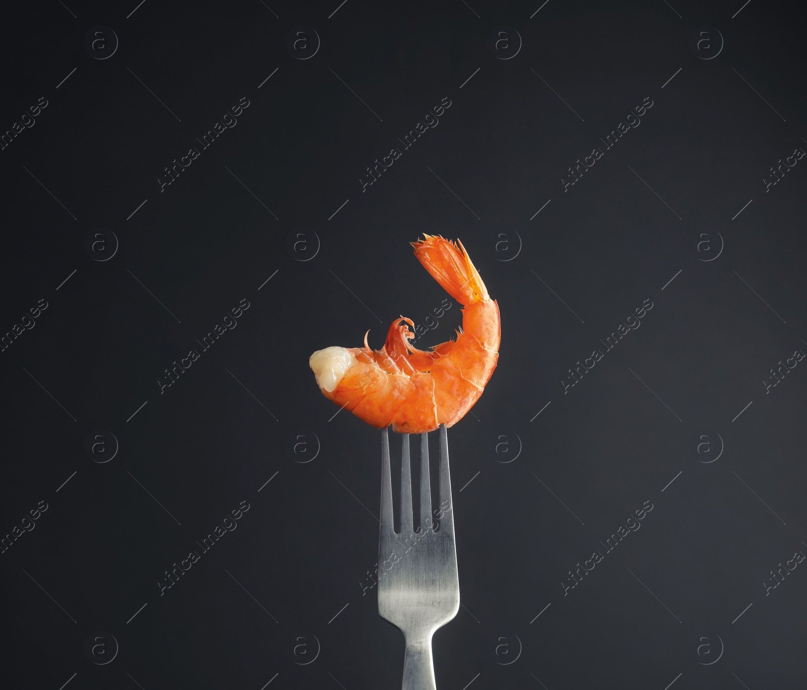 Photo of Fork with delicious shrimp on dark background