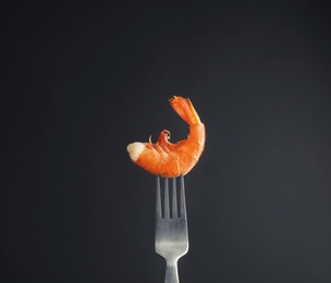 Photo of Fork with delicious shrimp on dark background