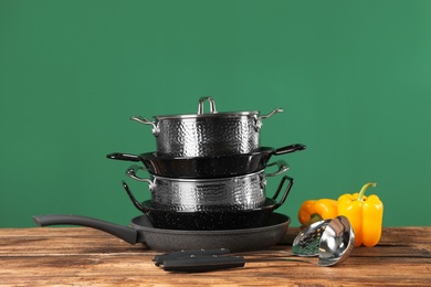 Photo of Set of clean cookware and utensils on table against color background