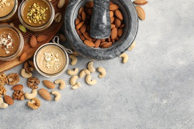 Photo of Making nut butters from different nuts. Flat lay composition with space for text on light grey table
