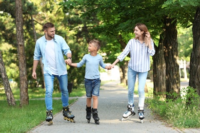 Young happy family roller skating in summer park