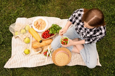 Photo of Girl having picnic on green grass in park, above view