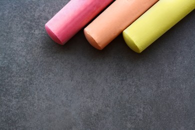 Photo of Colorful chalk sticks on black surface, flat lay. Space for text
