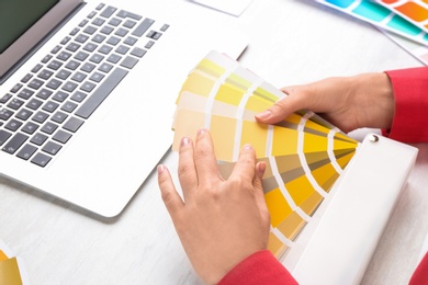 Photo of Woman with palette samples at white table, closeup