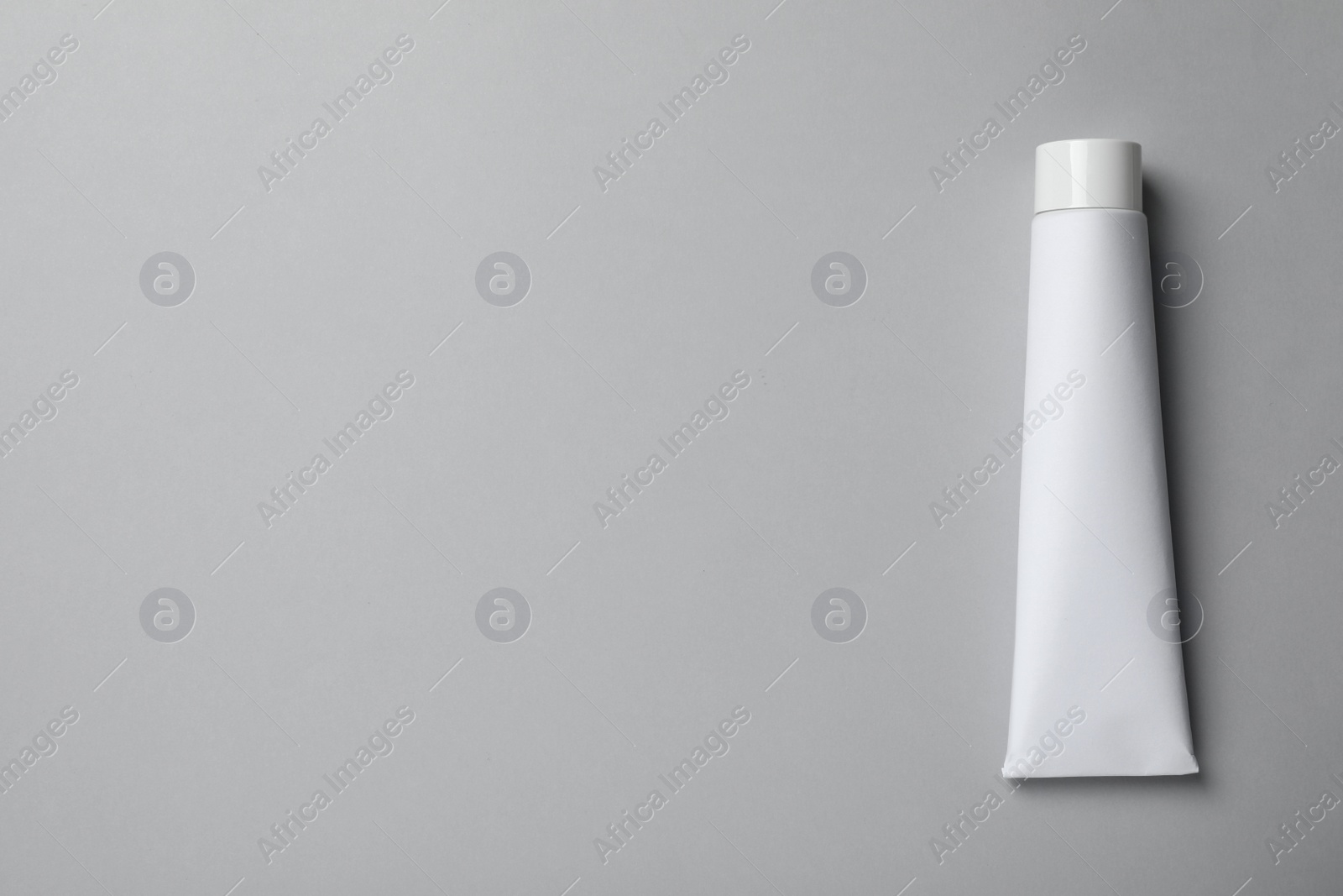 Photo of Blank tube of toothpaste on light grey background, top view. Space for text