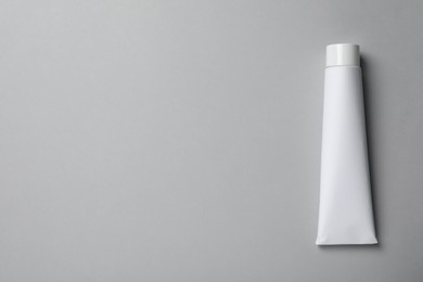 Photo of Blank tube of toothpaste on light grey background, top view. Space for text