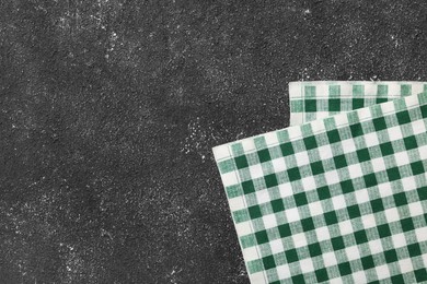 Photo of Green checkered tablecloth on black textured table, top view. Space for text