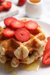 Photo of Delicious Belgian waffles with strawberries and honey on plate, closeup