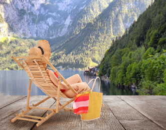 Image of Young woman relaxing on sun lounger near river and mountains. Luxury vacation 