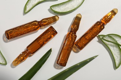 Skincare ampoules and cut aloe leaves on white background, flat lay