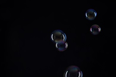 Photo of Many beautiful soap bubbles on black background. Space for text