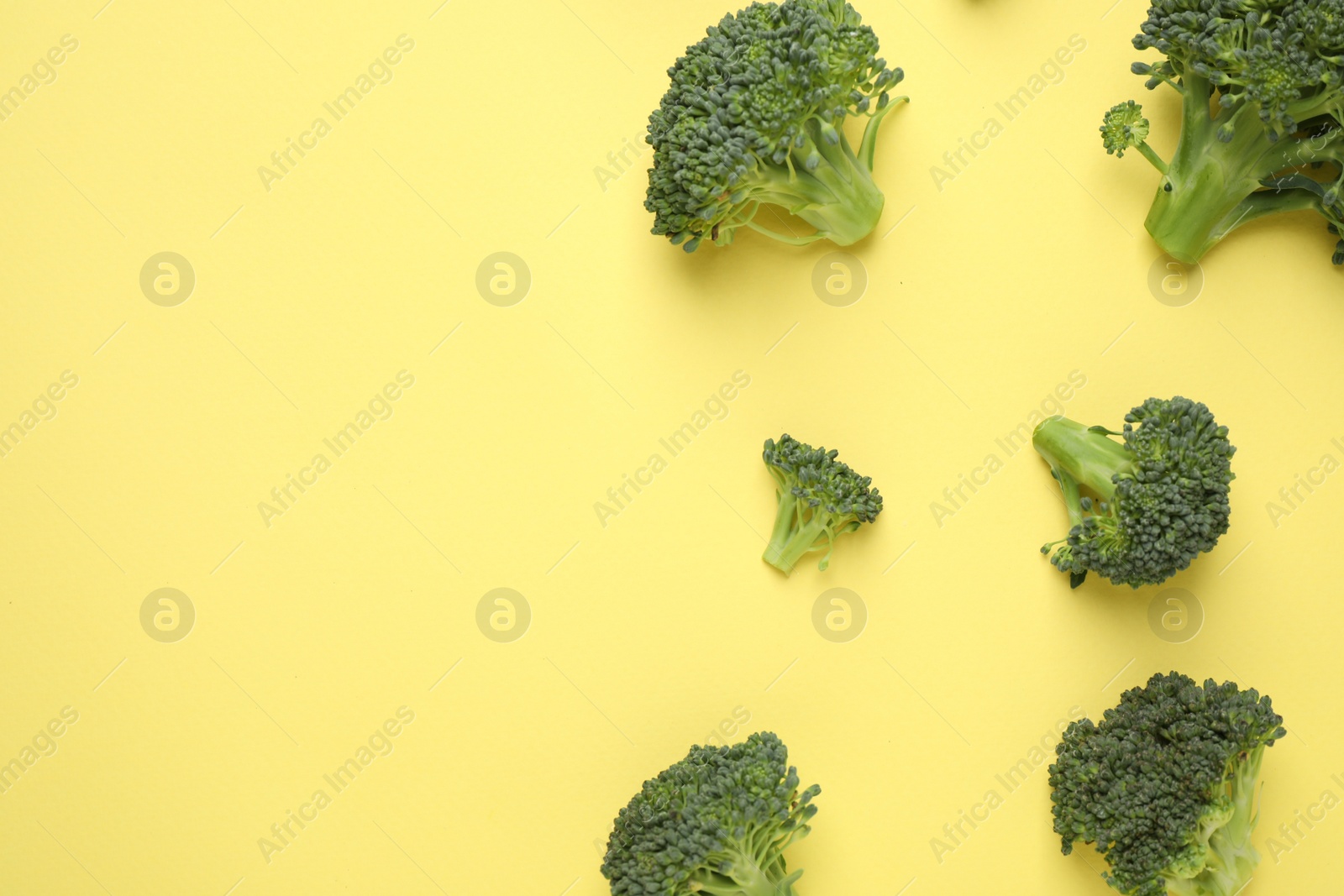 Photo of Fresh tasty broccoli on yellow background, flat lay. Space for text