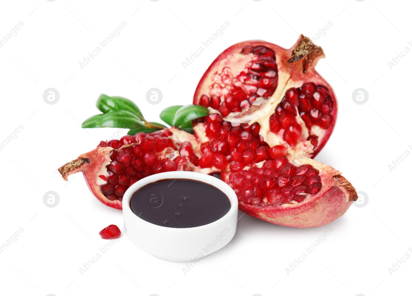 Photo of Tasty pomegranate sauce in bowl, leaves and fruits isolated on white