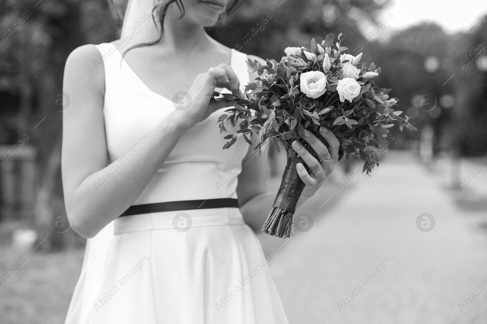 Photo of Woman in wedding gown with beautiful bridal bouquet outdoors, black and white effect