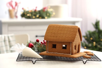 Photo of Gingerbread house and icing on white table. Christmas treat