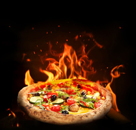 Image of Hot tasty pizza with fire flames on dark background. Image for menu or poster