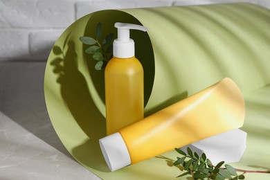Photo of Different cleansers and leaves on grey table, space for text. Cosmetic product