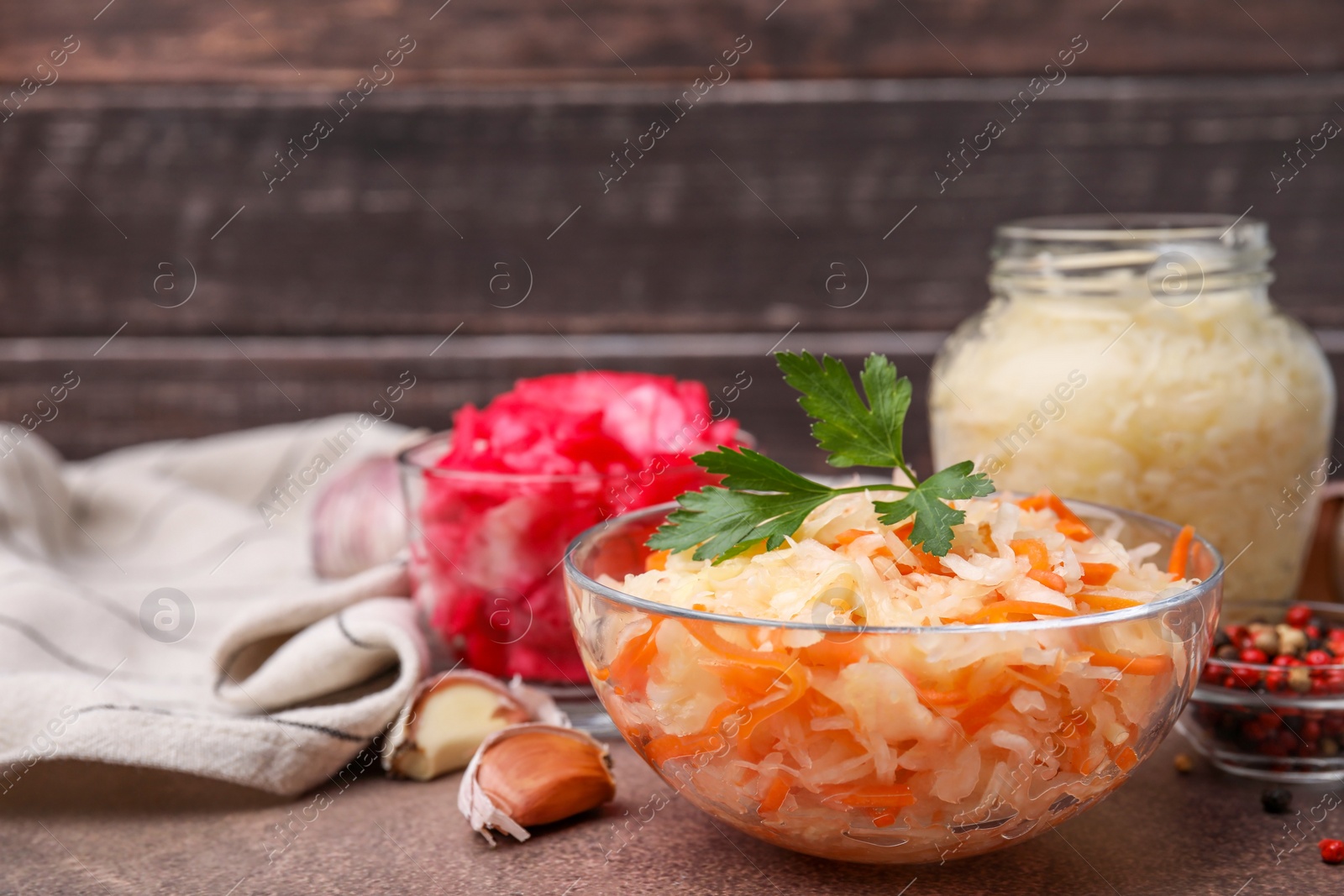 Photo of Delicious sauerkraut prepared according to different recipes on brown table, closeup. Space for text