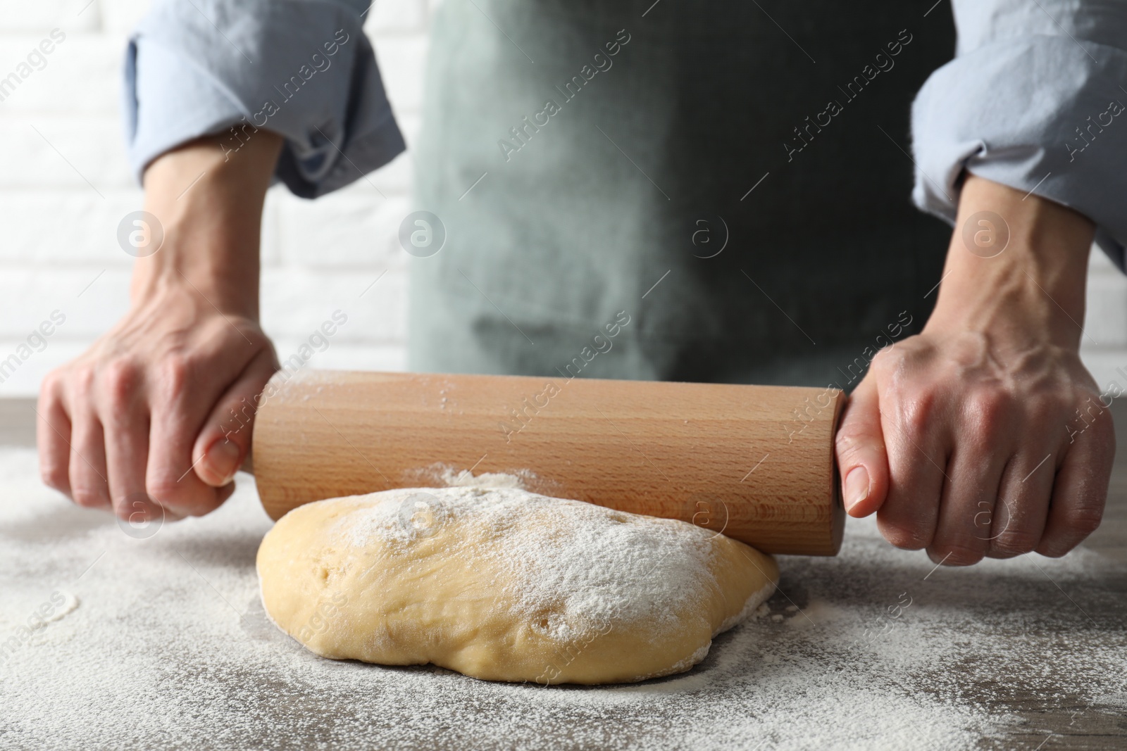 Photo of Woman rolling raw dough at table, closeup