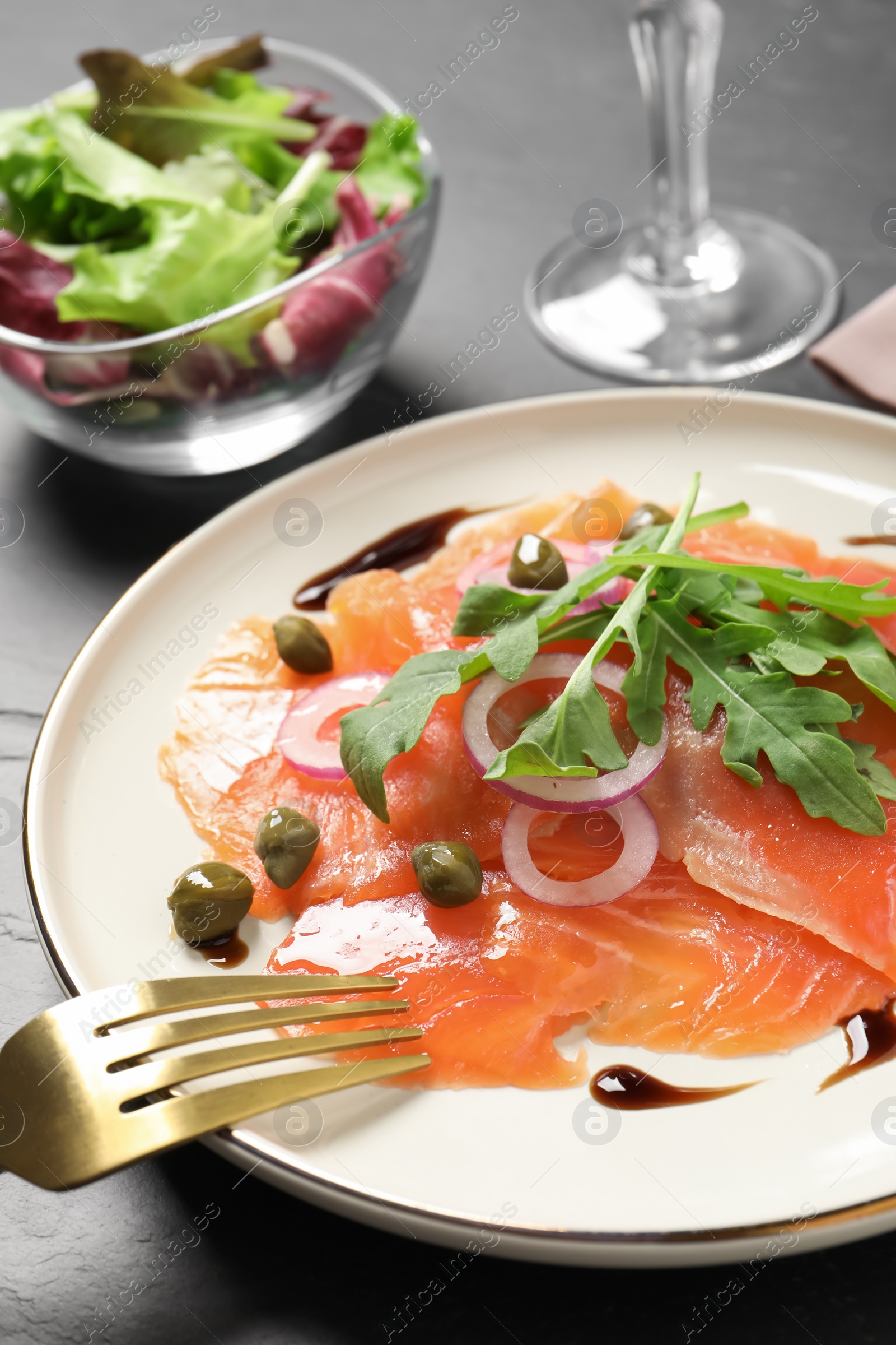 Photo of Delicious salmon carpaccio served on black table, closeup