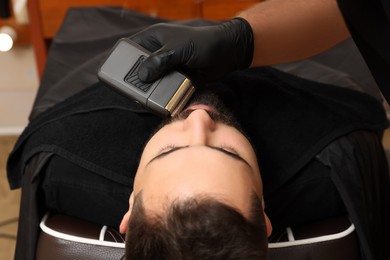 Photo of Professional hairdresser working with client in barbershop, closeup