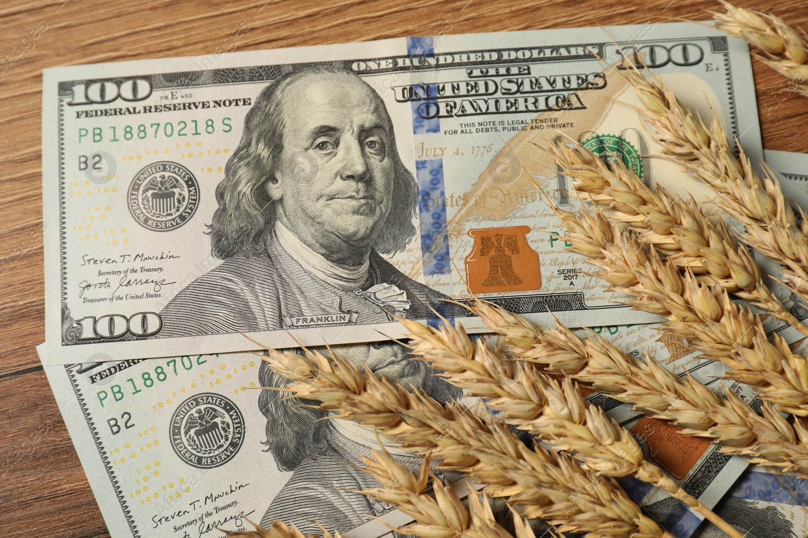 Photo of Dollar banknotes and wheat ears on wooden table, top view. Agricultural business