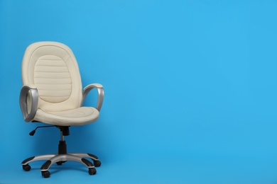 Comfortable office chair on light blue background, space for text