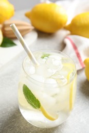 Photo of Glass of cold lemonade on light grey table, closeup