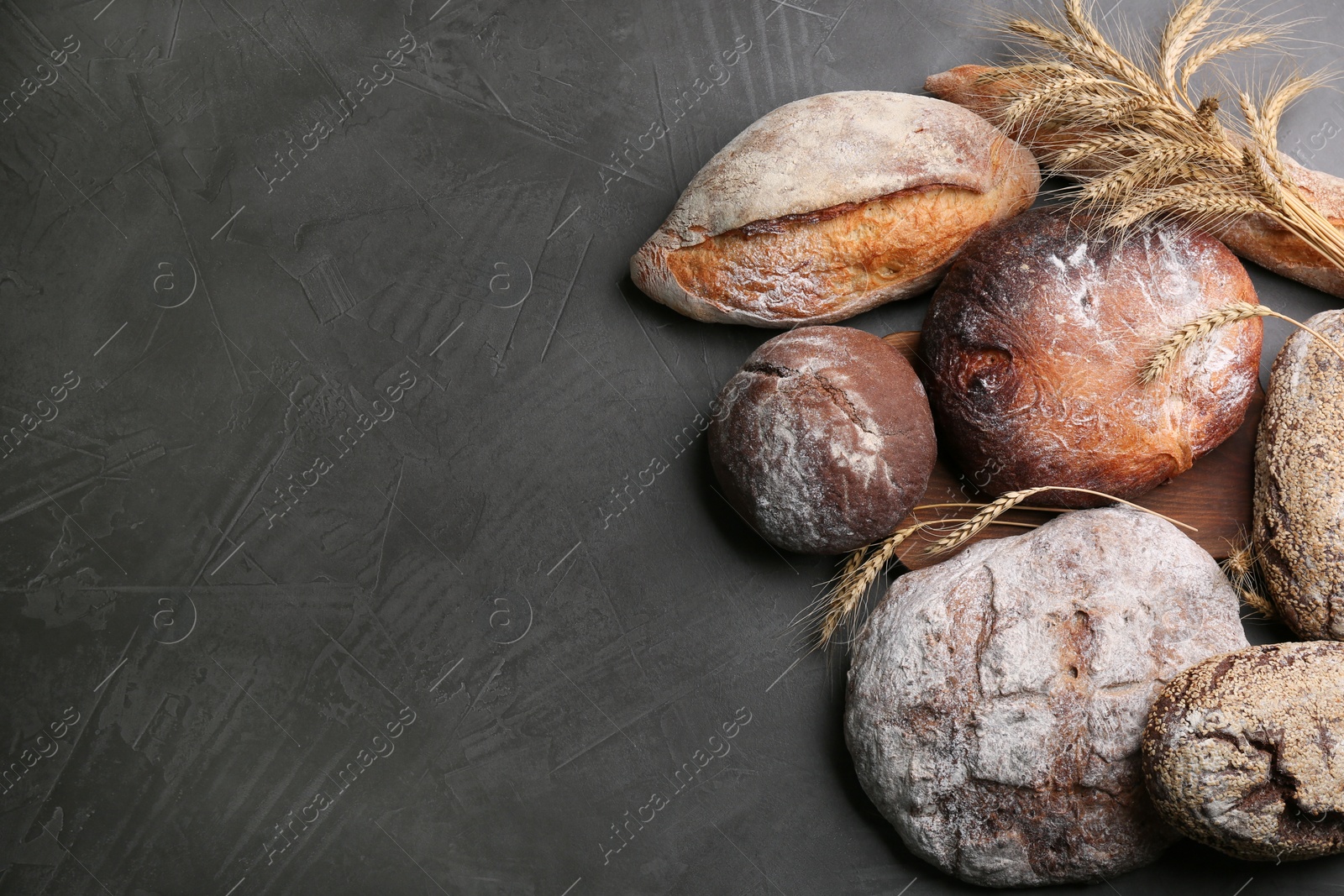 Photo of Different kinds of fresh bread on grey table, flat lay. Space for text