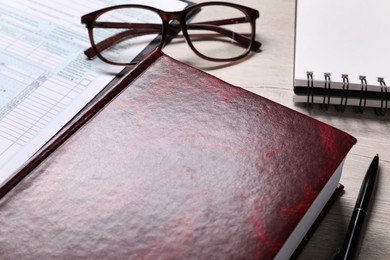 Law. Book, glasses, form and stationery on wooden table, closeup