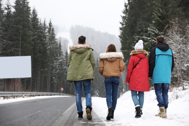 Group of friends walking near snowy forest. Winter vacation