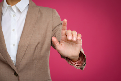 Woman touching something against pink background, focus on hand