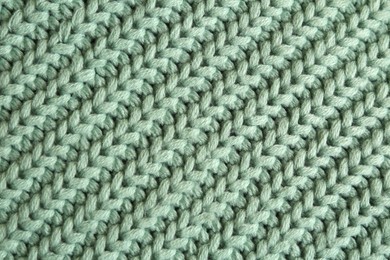 Photo of Beautiful pale green knitted fabric as background, top view