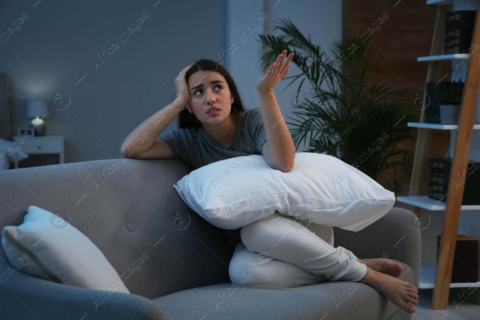 Photo of Young woman suffering from noisy neighbours on sofa in living room