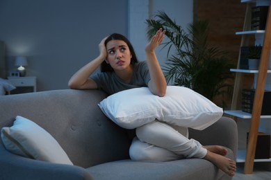 Photo of Young woman suffering from noisy neighbours on sofa in living room