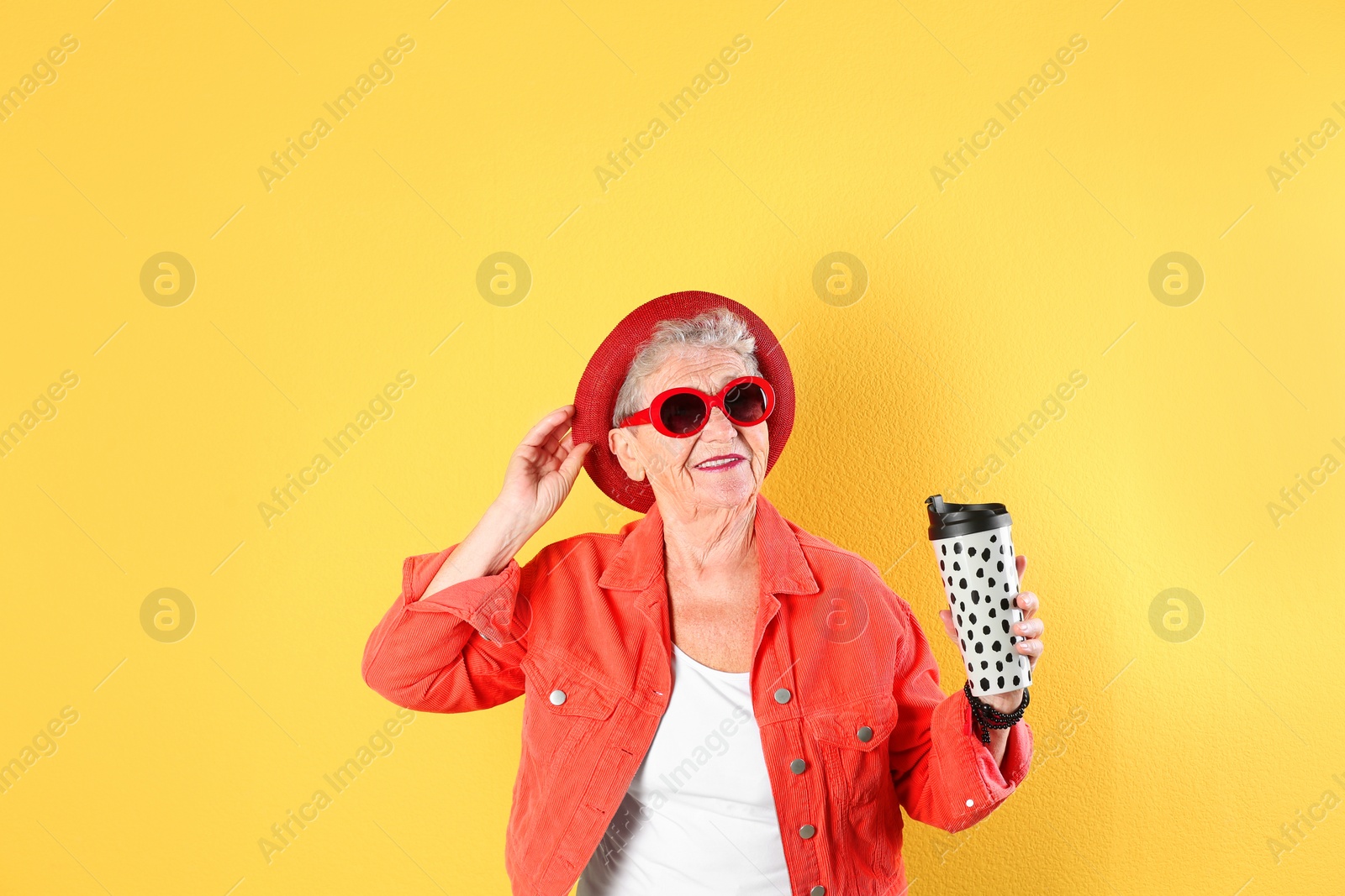 Photo of Portrait of cool grandmother with drink on color background