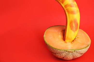 Photo of Fresh banana with lipstick marks and melon on red background, space for text. Sex concept