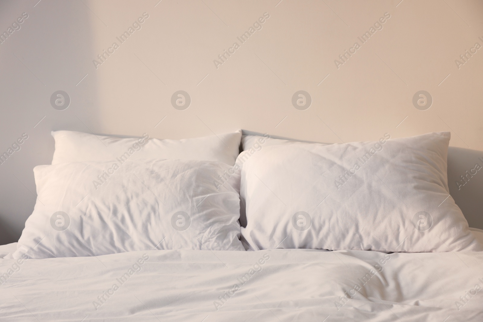 Photo of White soft pillows on bed in room