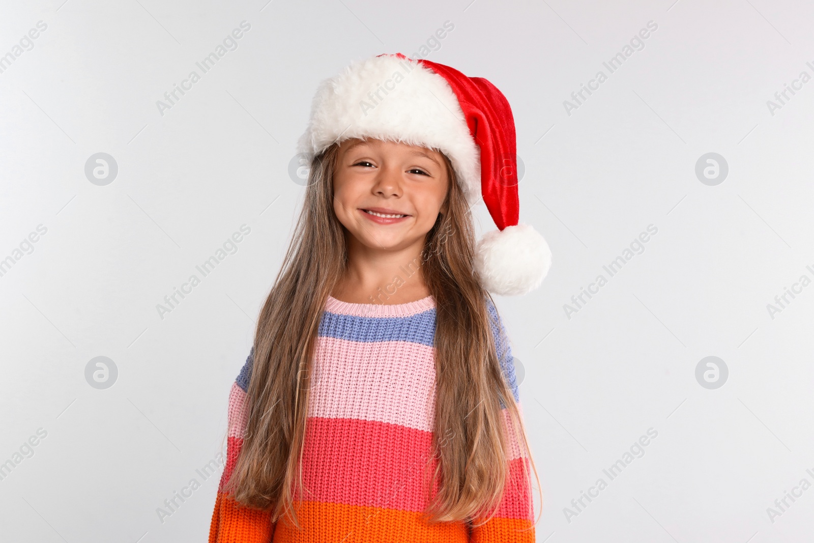 Photo of Happy little child in Santa hat on light grey background. Christmas celebration