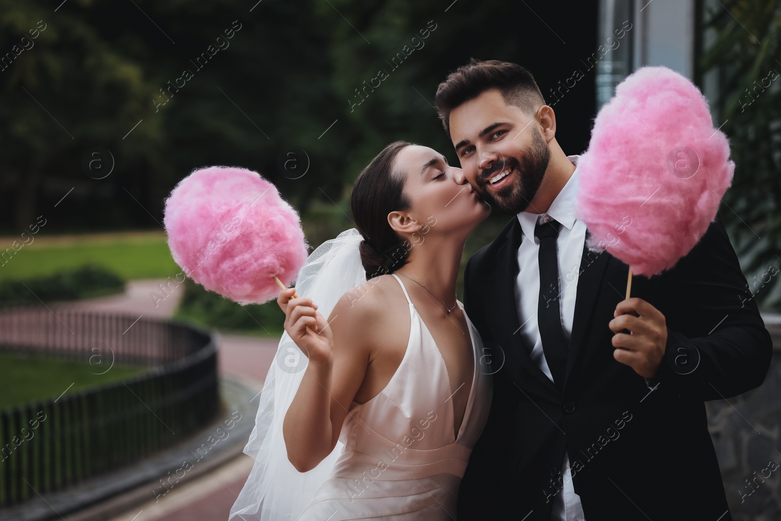 Image of Happy newlywed couple with cotton candies outdoors