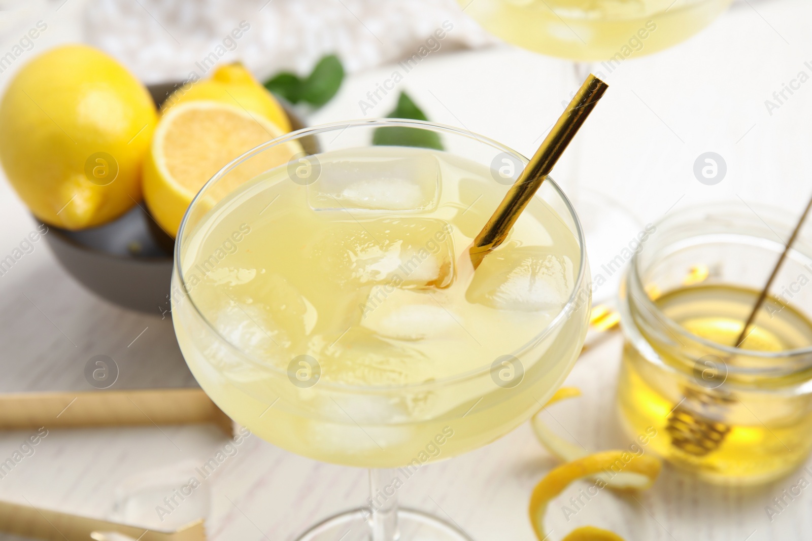 Photo of Delicious bee's knees cocktail and ingredients on white wooden table