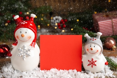 Photo of Funny decorative snowmen and blank red card on table