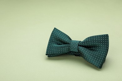 Stylish bow tie with polka dot pattern on pale green background, space for text