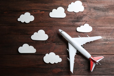 Photo of Toy airplane and clouds on wooden background, flat lay