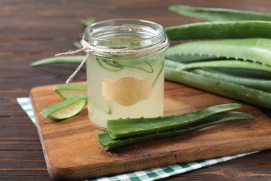 Photo of Fresh aloe juice in jar and leaves on wooden table, closeup