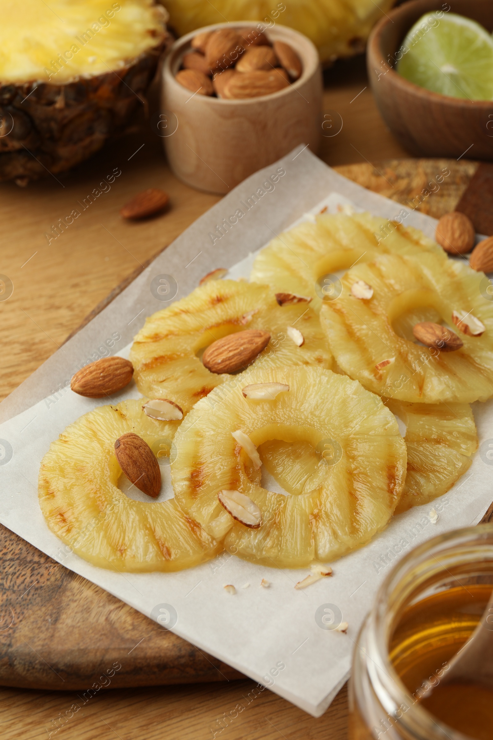 Photo of Tasty grilled pineapple slices and almonds on wooden table