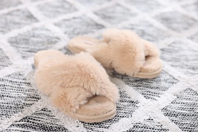 Photo of Beige soft slippers on beautiful carpet, closeup