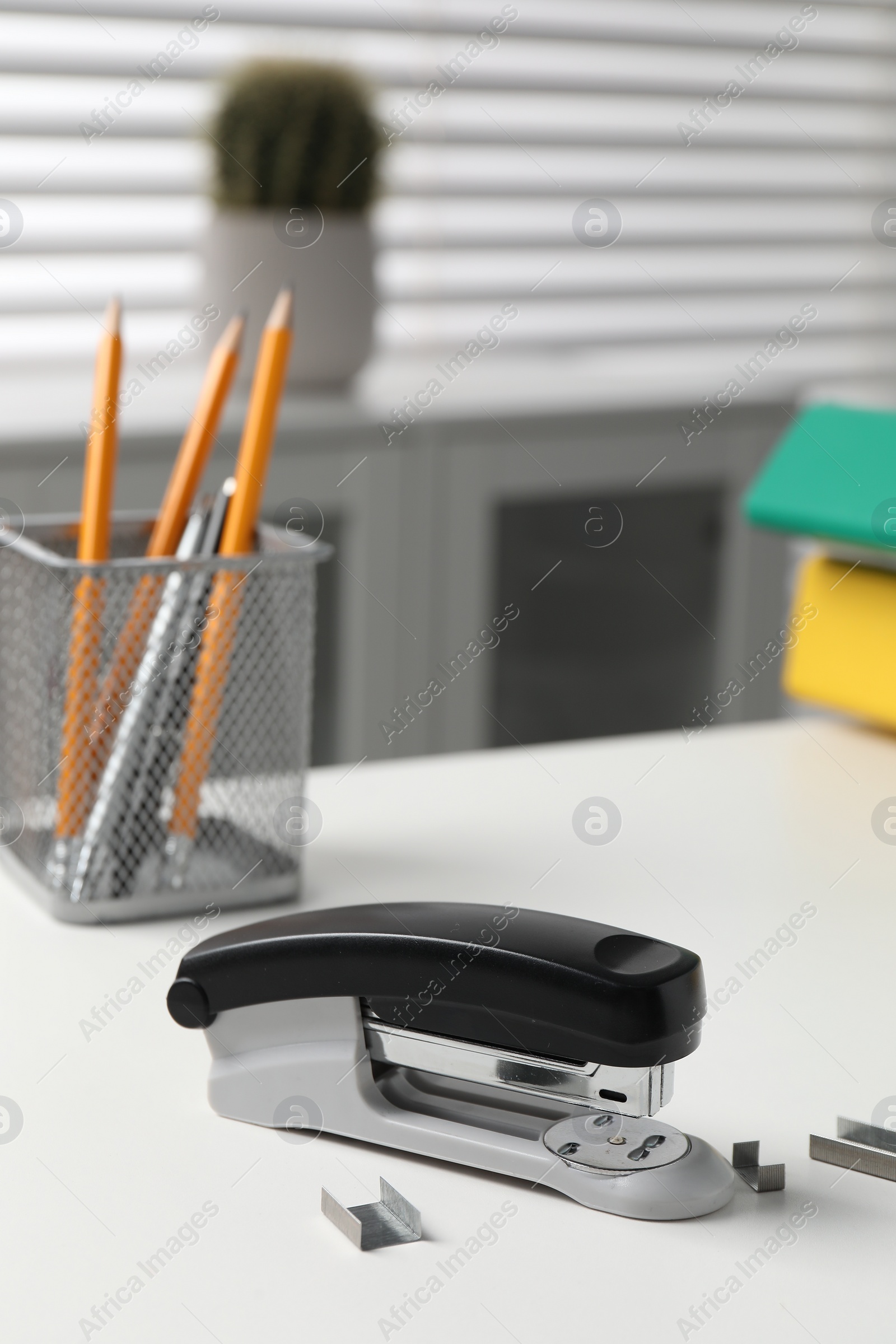 Photo of Stapler and metal staples on white table indoors