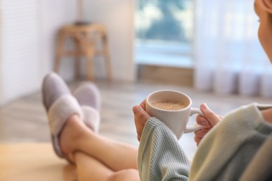Woman with cup of aromatic coffee relaxing at home, closeup. Space for text